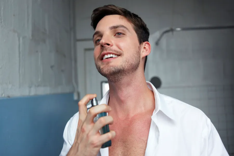 Man putting on cologne in urban loft bathroom