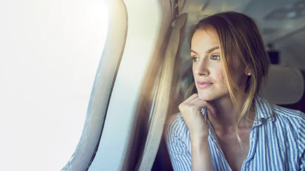 Serious woman looking out of airplane window