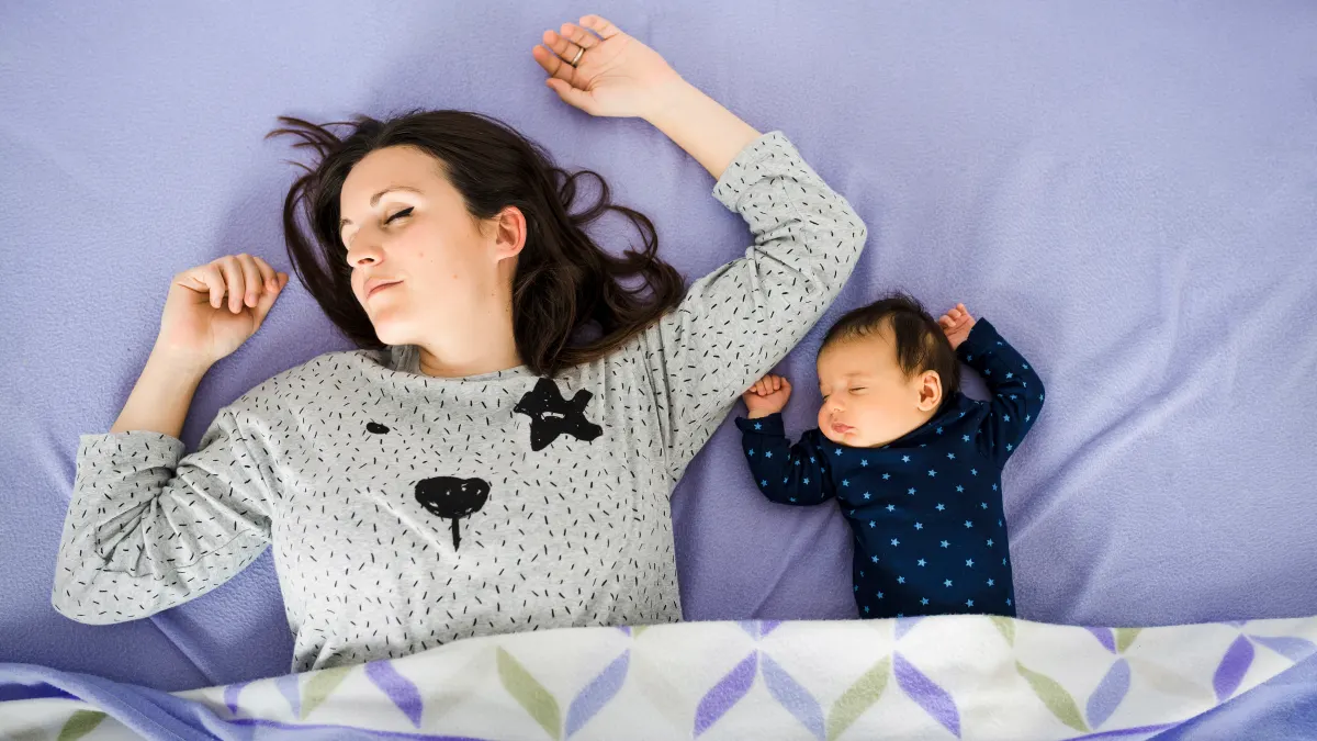 mother and baby laying down on bed