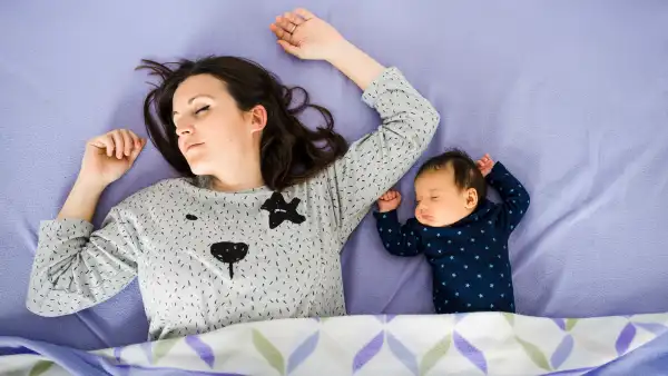 mother and baby laying down on bed