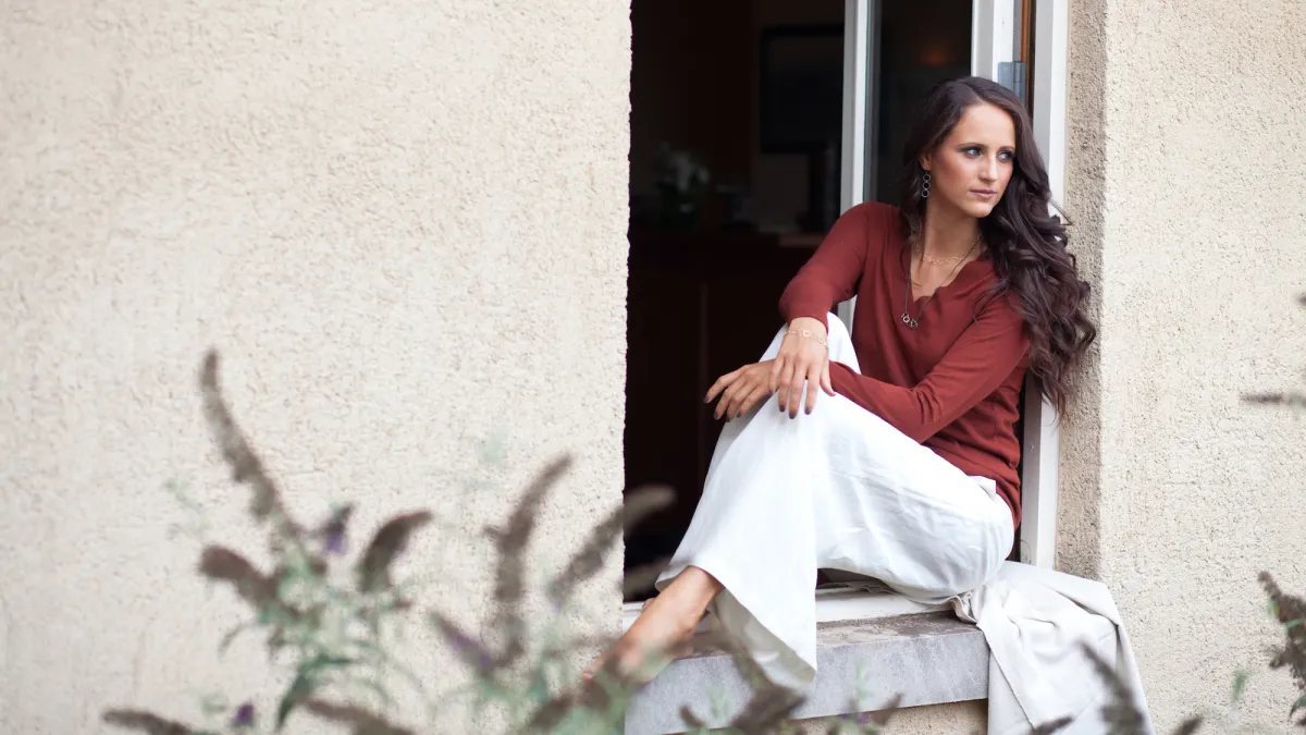 Young woman sitting in windowsill