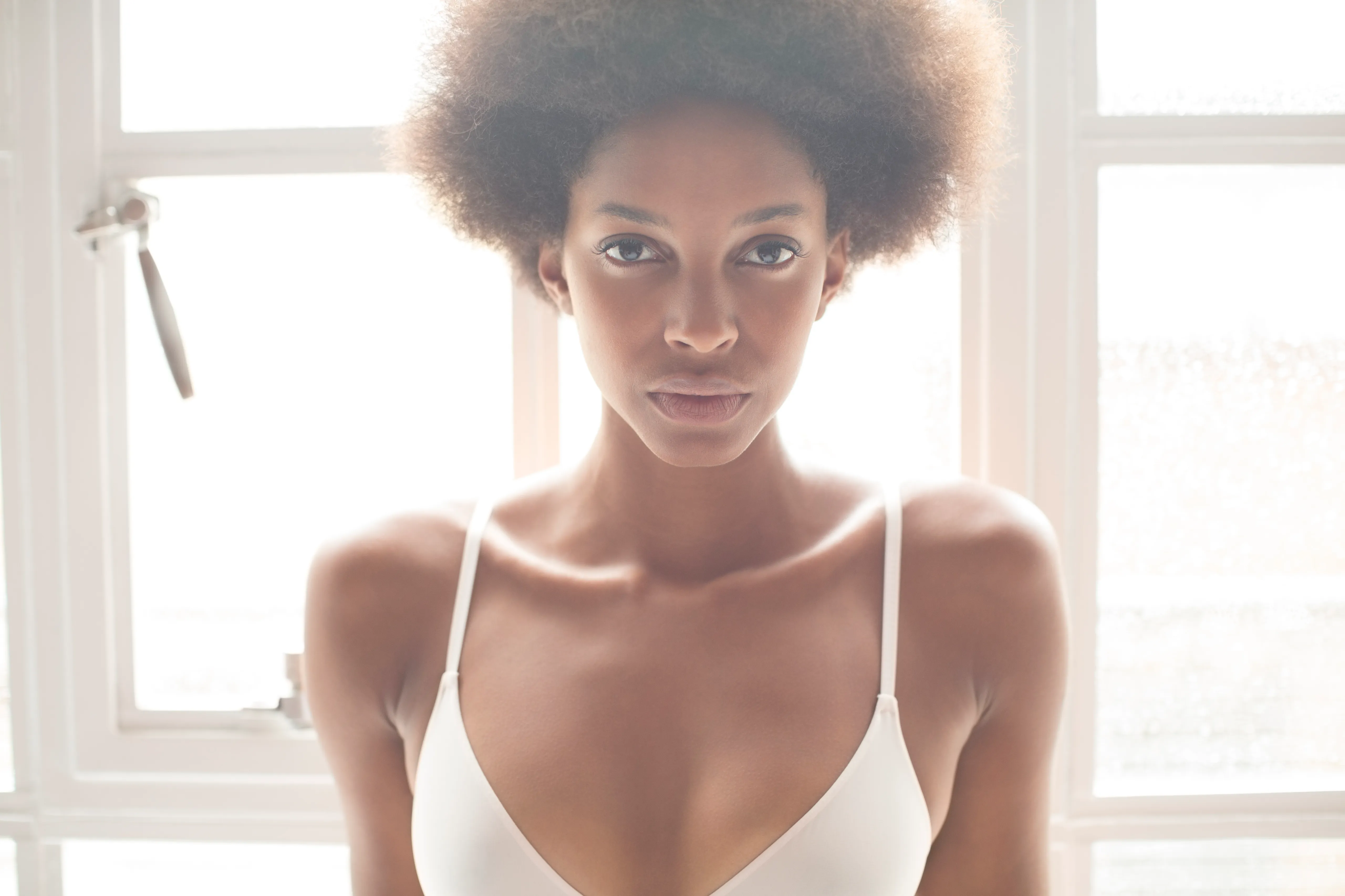 Woman wearing bra in front of window