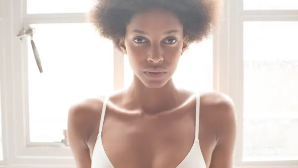 Woman wearing bra in front of window