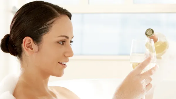 Close-up of a young woman pouring white wine into a wineglass