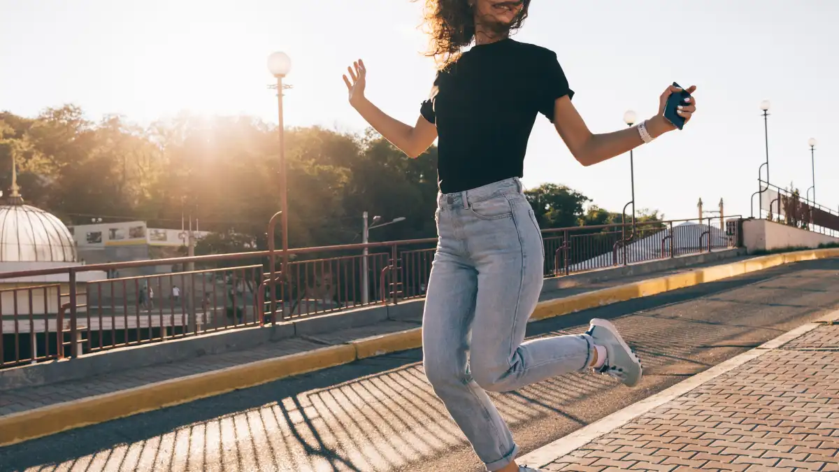 Happy girl with curly brown hair jumping in the city