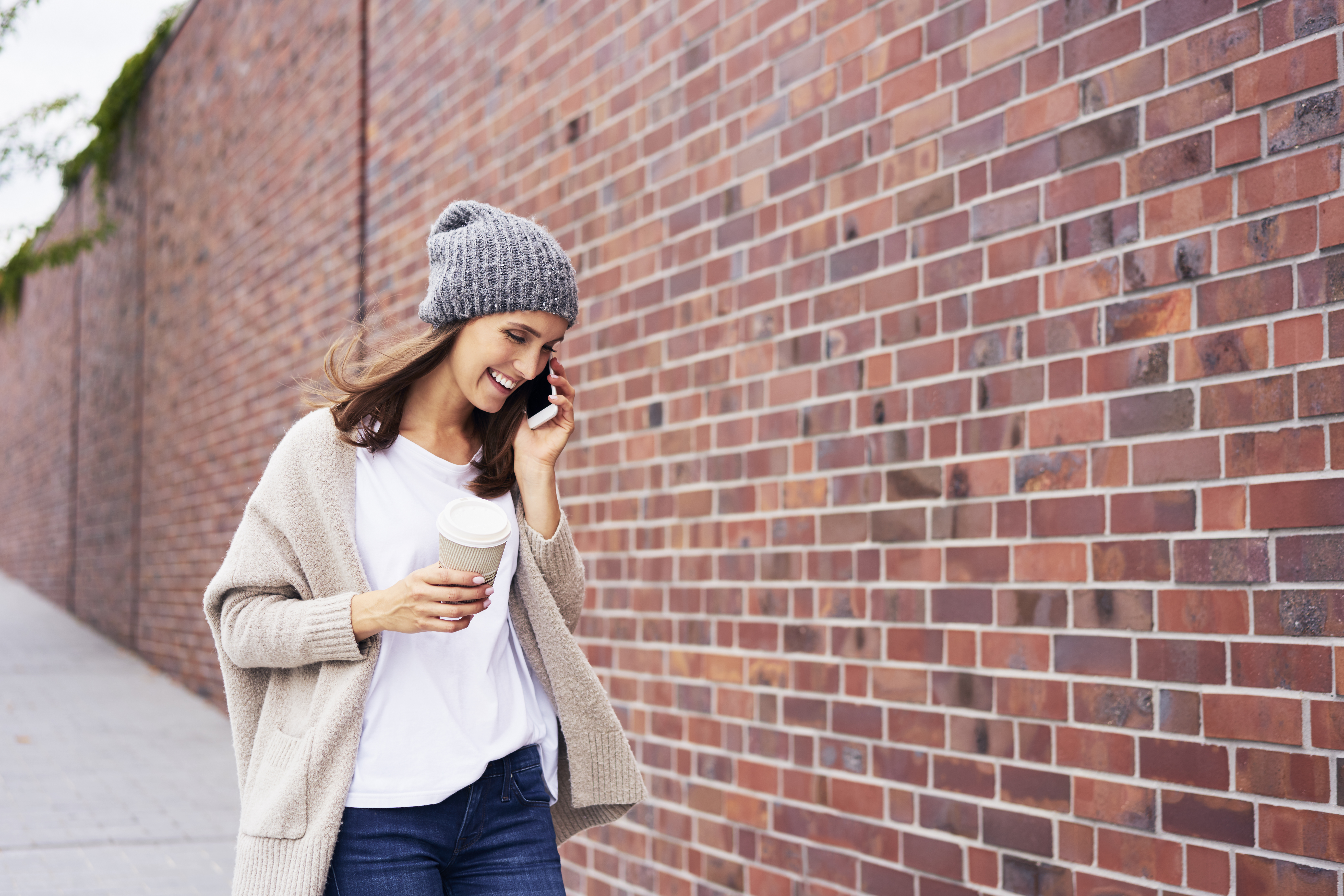 Happy woman with coffee to go on the phone