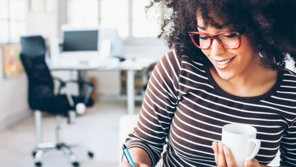 woman sitting at desk working with curly hair, red glasses, office chair