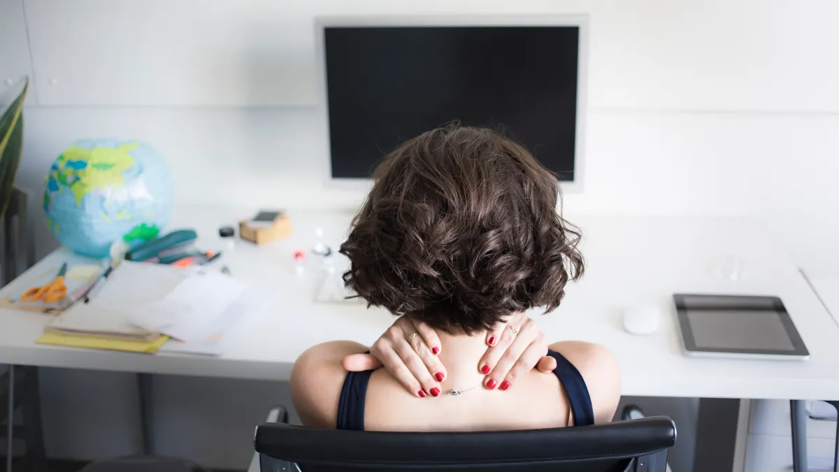 Young woman massaging her neck at desk