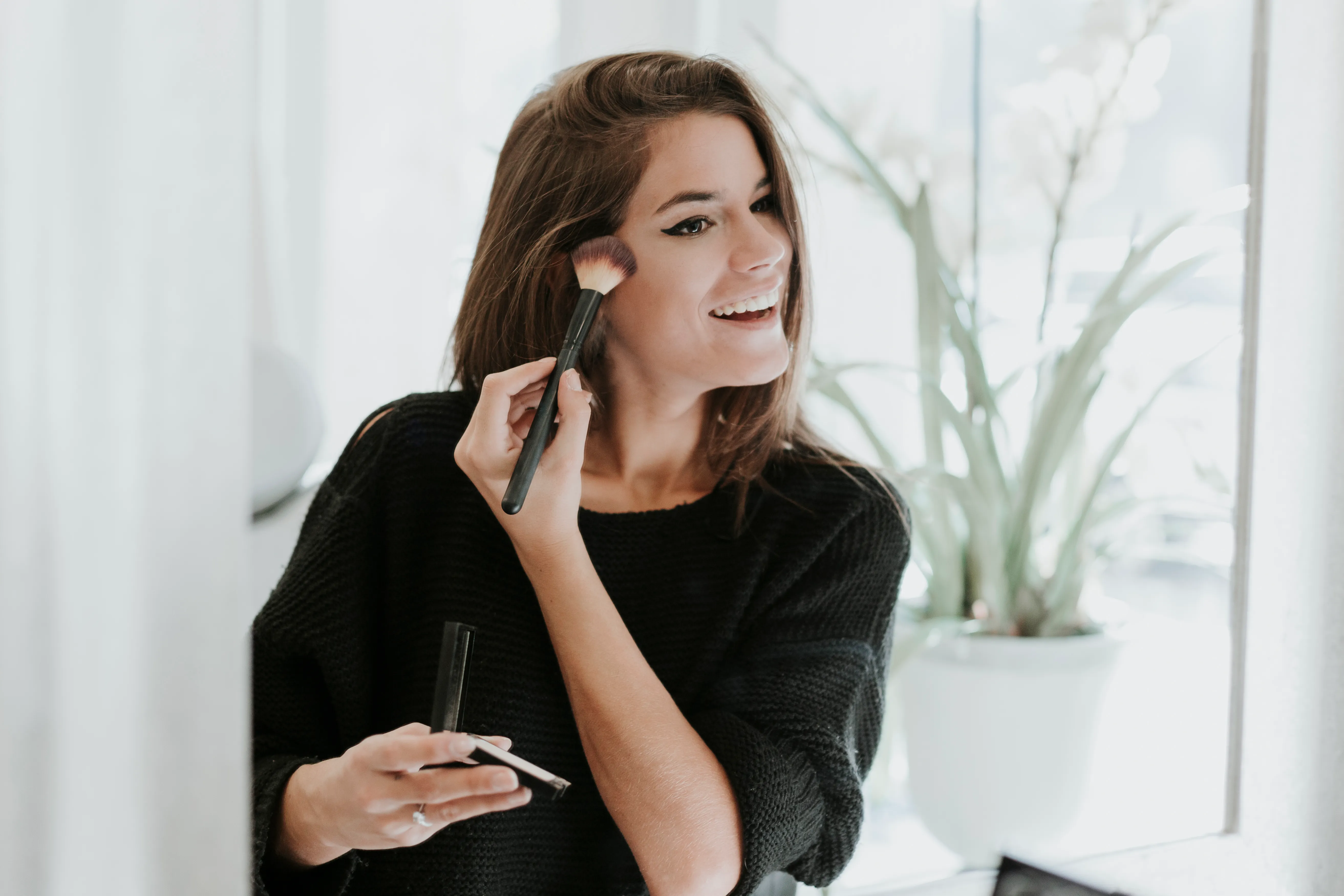 Mirror image of young woman applying Makeup