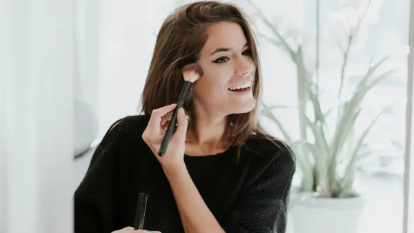 Mirror image of young woman applying Makeup