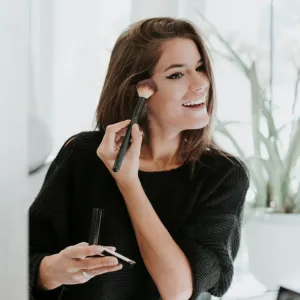 Mirror image of young woman applying Makeup
