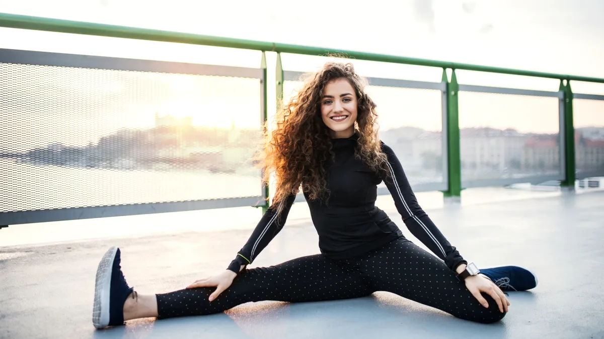 A sporty young woman stretching on the bridge outdoors in the city.