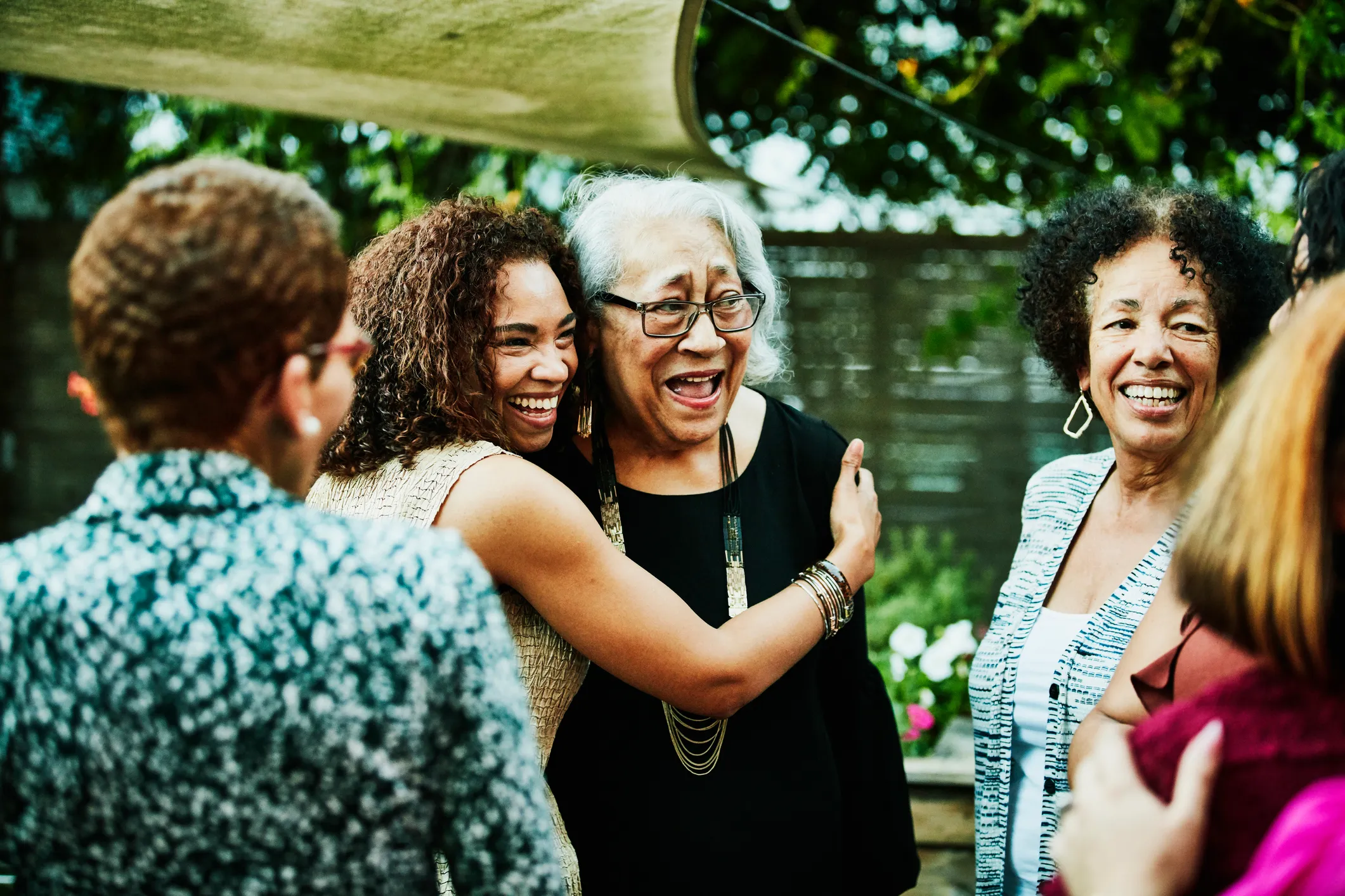 Mature daughter embracing senior mother after outdoor family dinner party