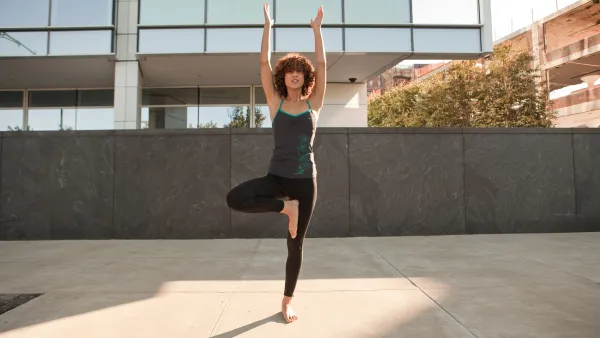 Young woman doing a tree pose on the pavement