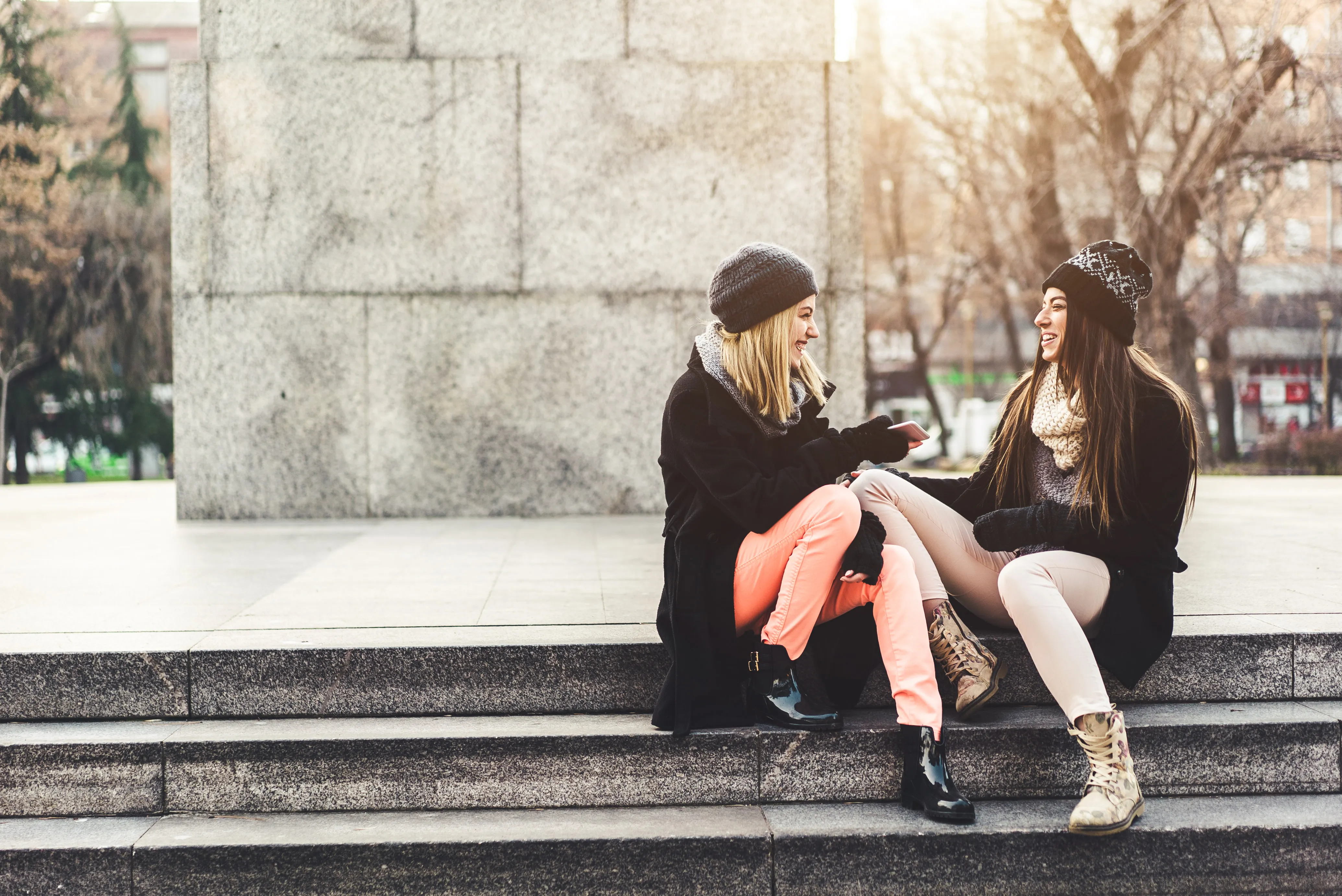 Two girls hanging out in some steps in a park on a sunny autumn day