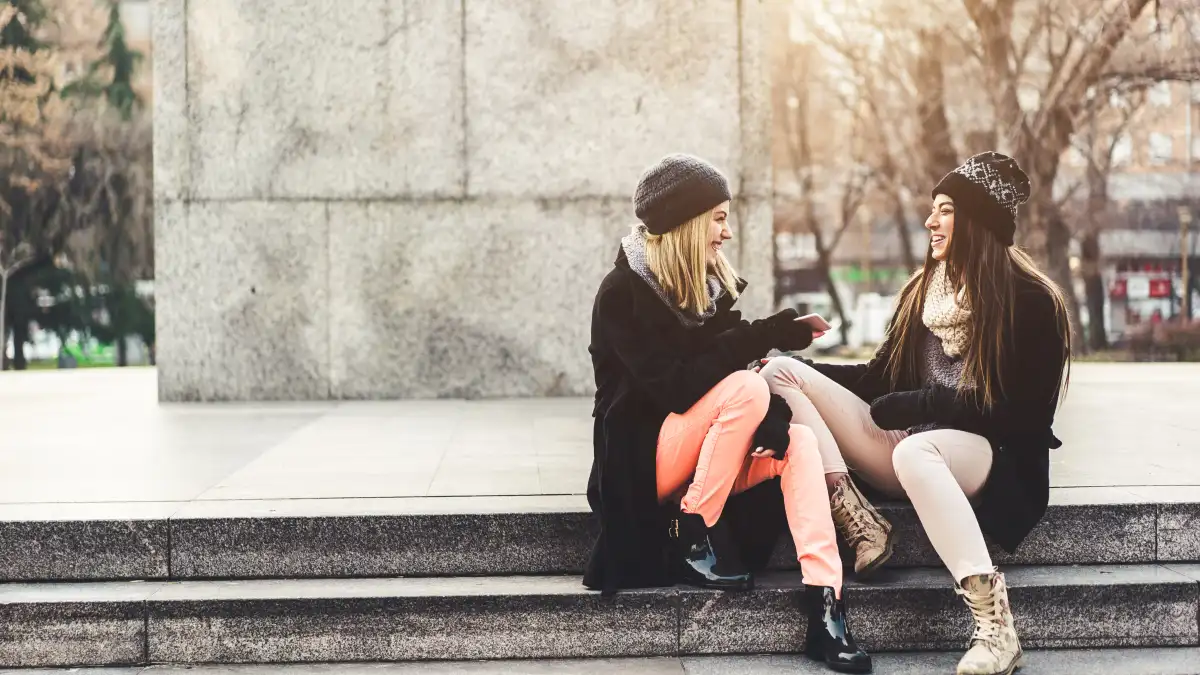 Two girls hanging out in some steps in a park on a sunny autumn day