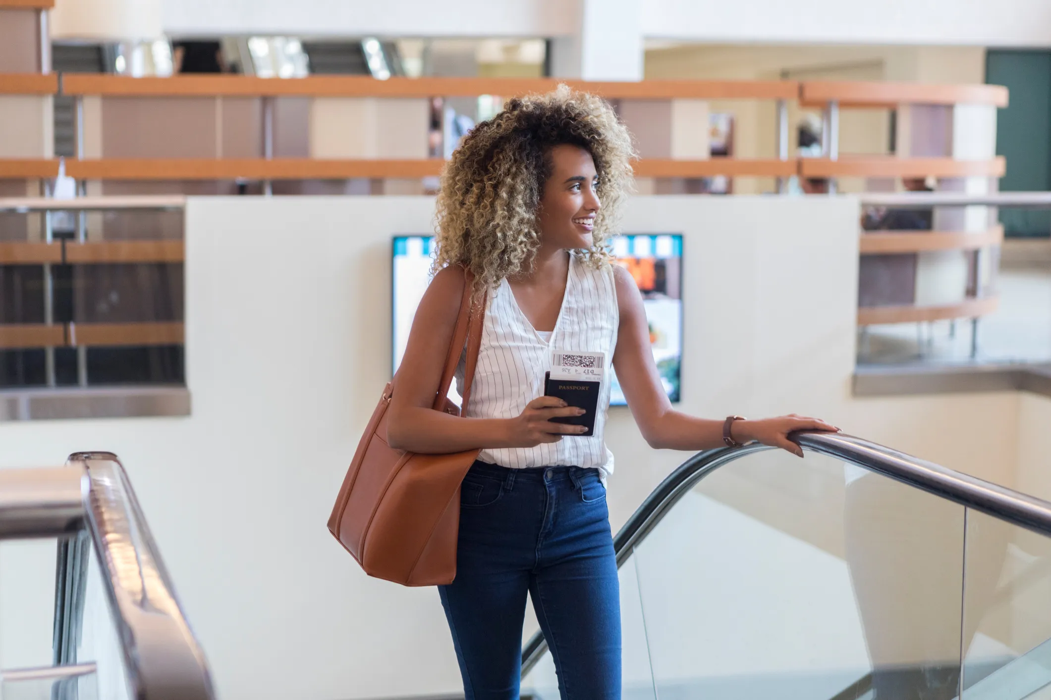 Young woman ascends escalator in airport terminal