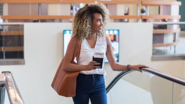 Young woman ascends escalator in airport terminal