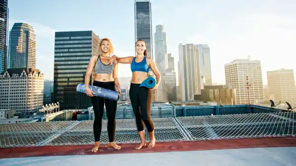 women holding yoga mats and exercising on roof