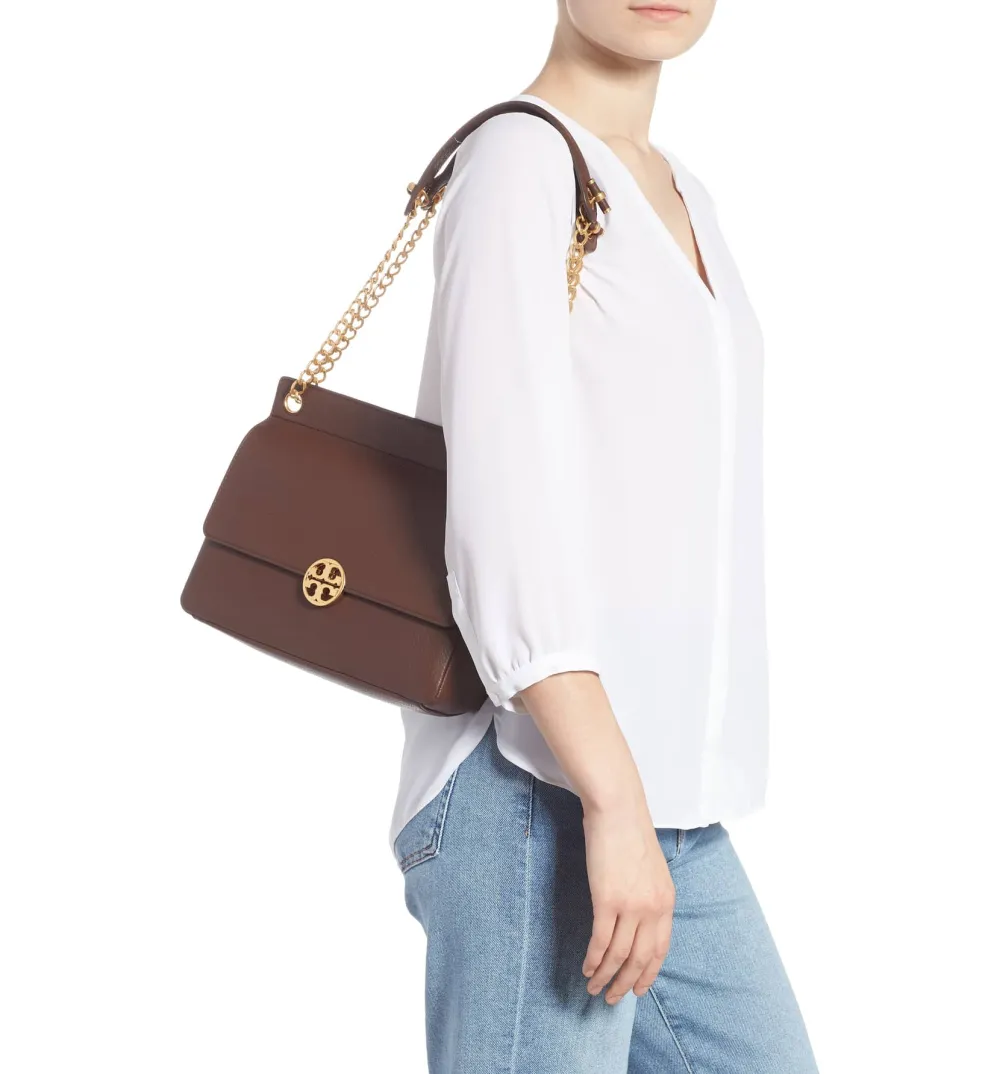 tory burch chelsea flap shoulder bag in brown on a model's shoulder