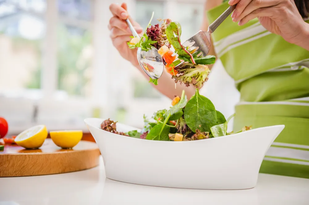 Hispanic woman tossing salad in domestic kitchen