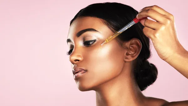 Woman applying serum to her face Splurge vs. Save: Lux Skin Care