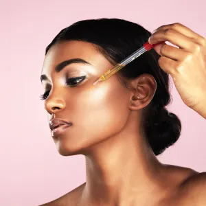 Woman applying serum to her face Splurge vs. Save: Lux Skin Care