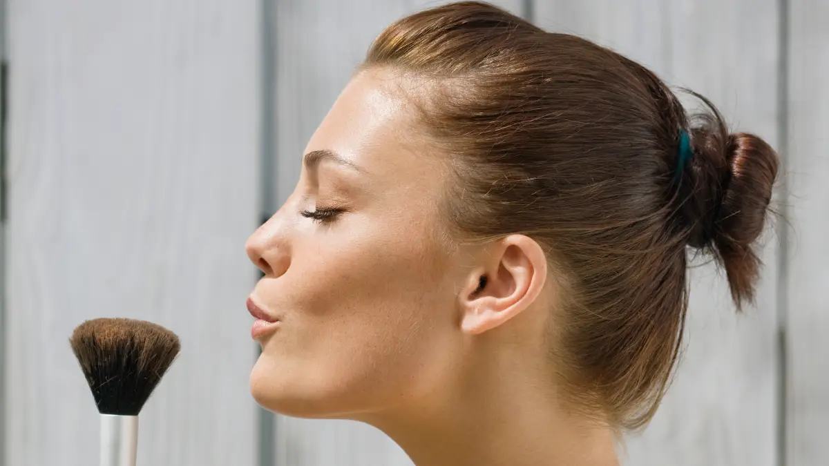 Woman blowing on a make-up brush