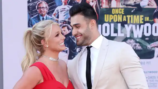 Sam-Asghari-Cooks-Steak-For-Britney-Spears Red Dress White Suit Black Tie Looking At Each Other