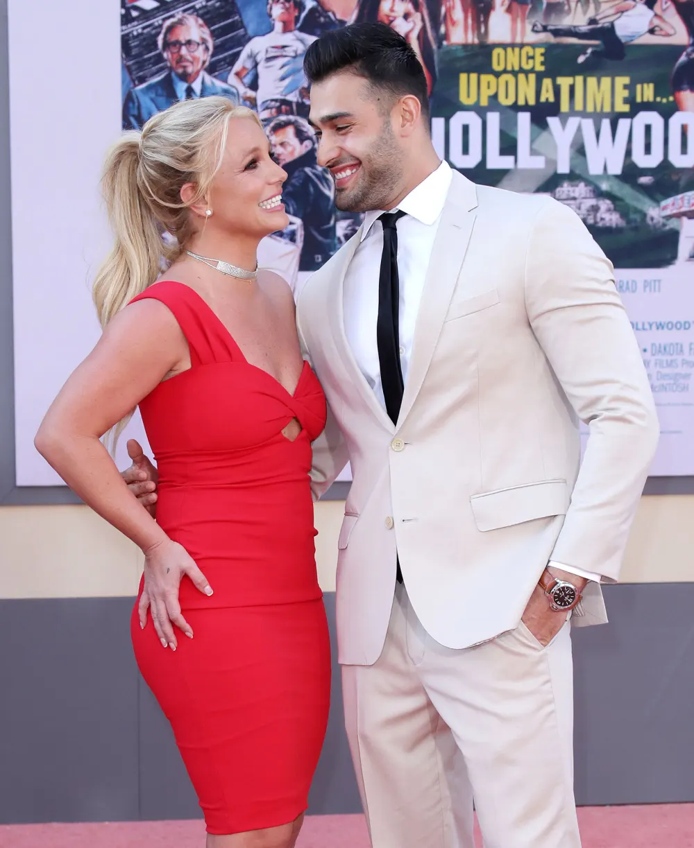 Sam-Asghari-Cooks-Steak-For-Britney-Spears Red Dress White Suit Black Tie Looking At Each Other