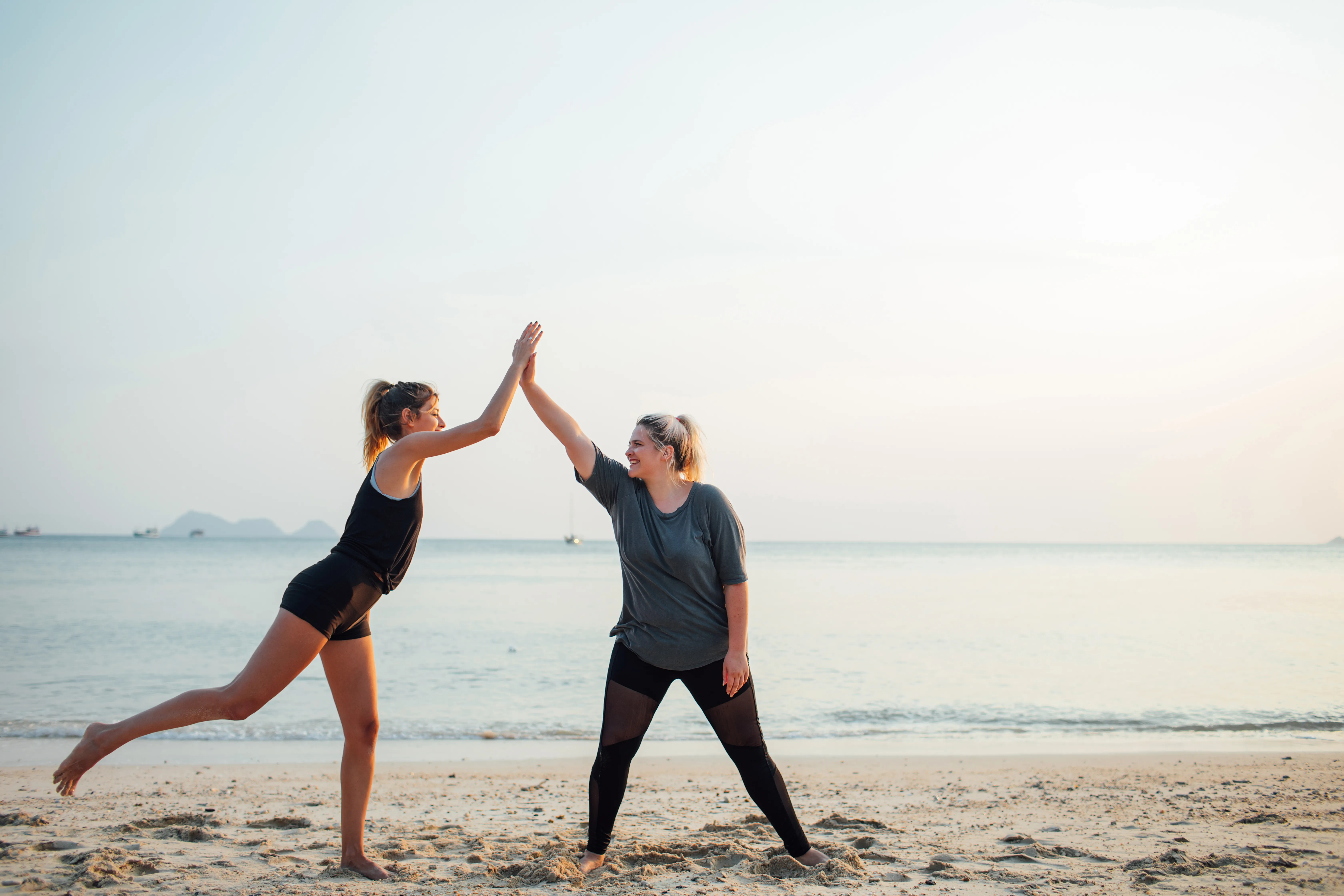 Two beautiful girls working out together on the beach