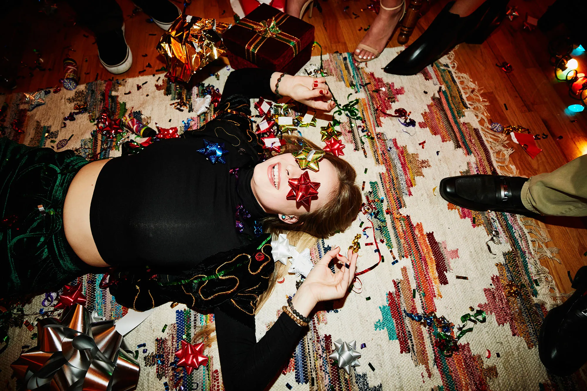 Laughing woman lying on floor with bows over eyes during holiday party with friends
