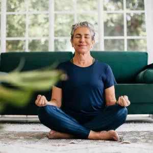 Relaxing the mind and finding inner peace with yoga: Senior woman meditating at home