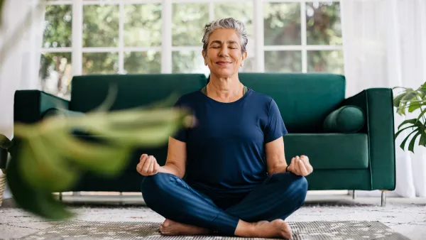 Relaxing the mind and finding inner peace with yoga: Senior woman meditating at home