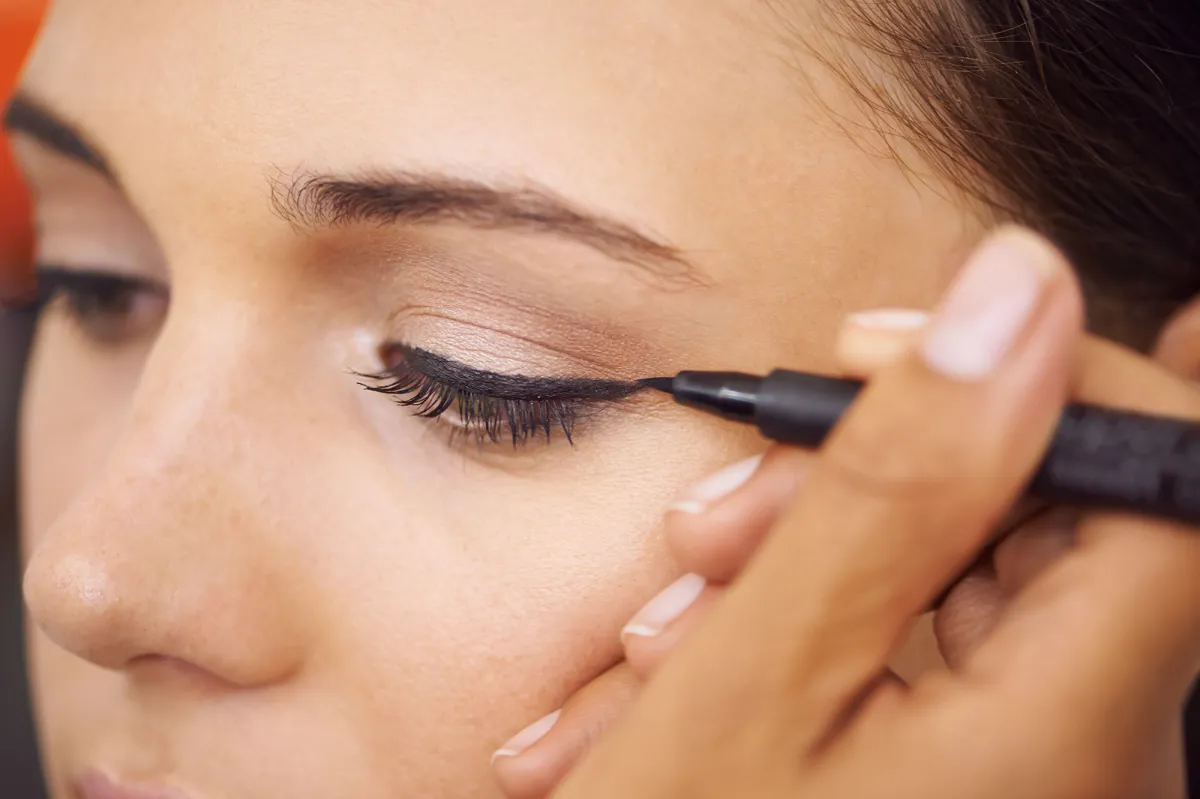 Closeup of a young woman getting liner applied to her eyes
