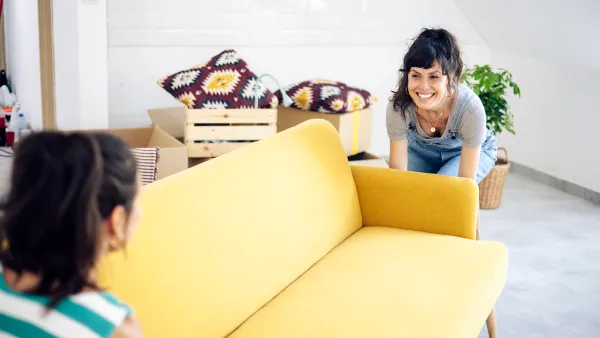 Happy twin sisters bringing the new furniture while moving into a new home.