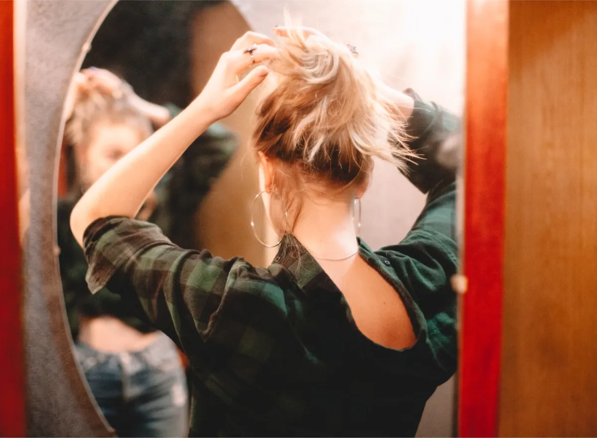 Woman putting her hair up in a mirror