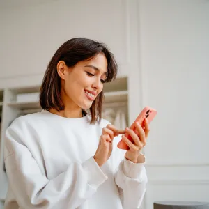 Saleswoman making orders using phone, working in design department of clothes store