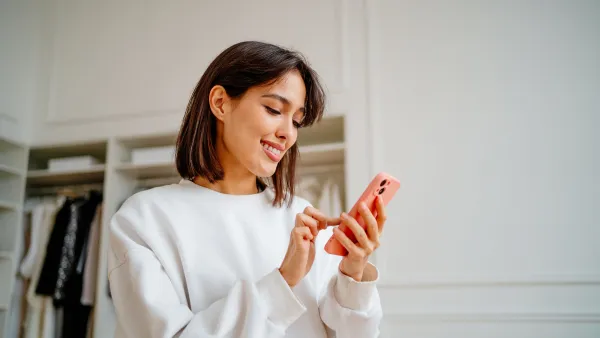 Saleswoman making orders using phone, working in design department of clothes store