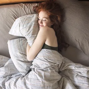 High angle view of smiling woman sleeping on bed at home