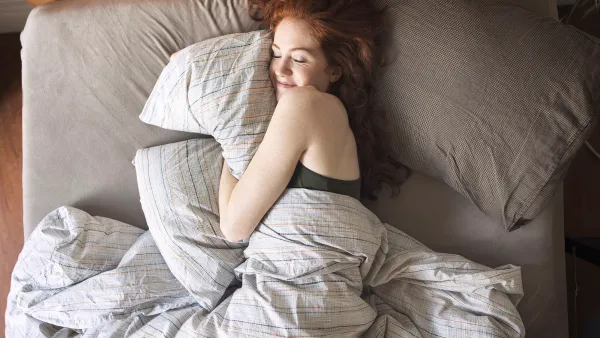 High angle view of smiling woman sleeping on bed at home