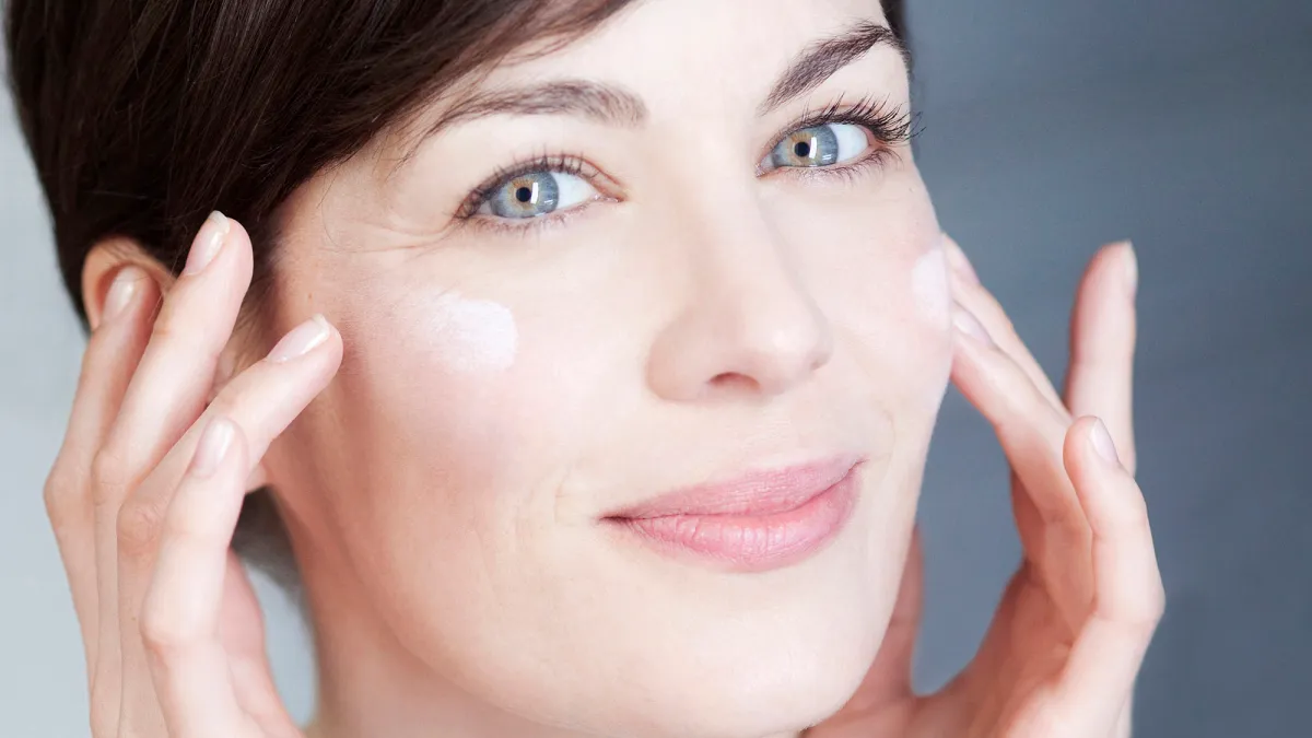 Woman applying cream on her face.