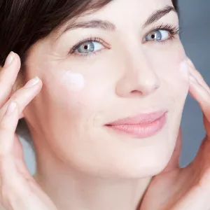 Woman applying cream on her face.