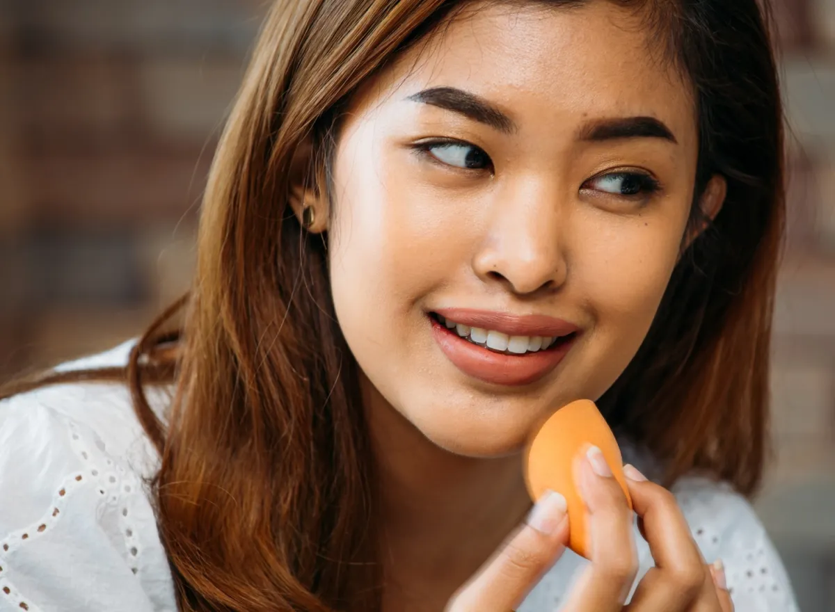 Woman applying foundation with a makeup sponge