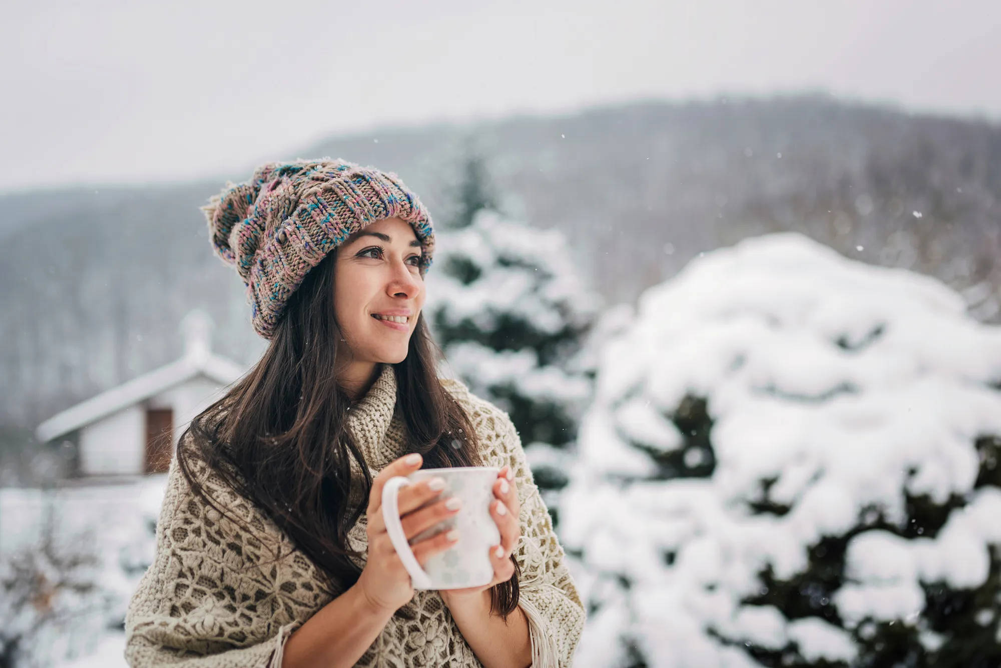 Young woman enjoying the snowy winter day with a cup of hot tea
