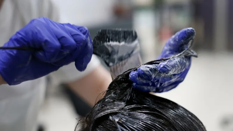 A woman wears a pair of gloves to color hair