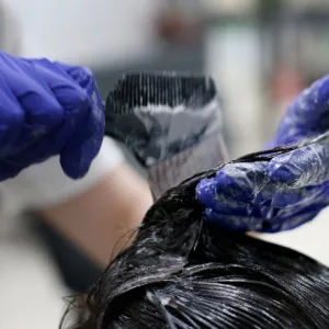 A woman wears a pair of gloves to color hair