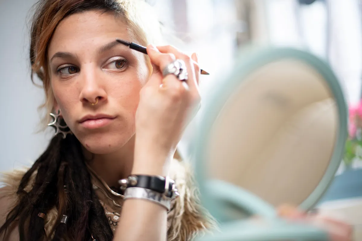 Beautiful young woman with a unique personal style putting on make-up