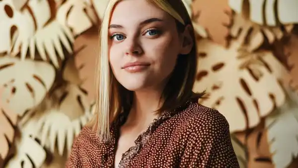 Portrait of a young girl on a background with palm leaves. Tropical background. Portrait of a woman.