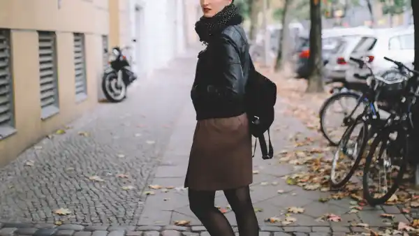 Vintage toned portrait of a young woman in Berlin, wearing a black leather jacket and a beige skirt, walking on the streets of Prenzlauer Berg, near Mitte in the late Autumn day. Street style, casual fashion concept.